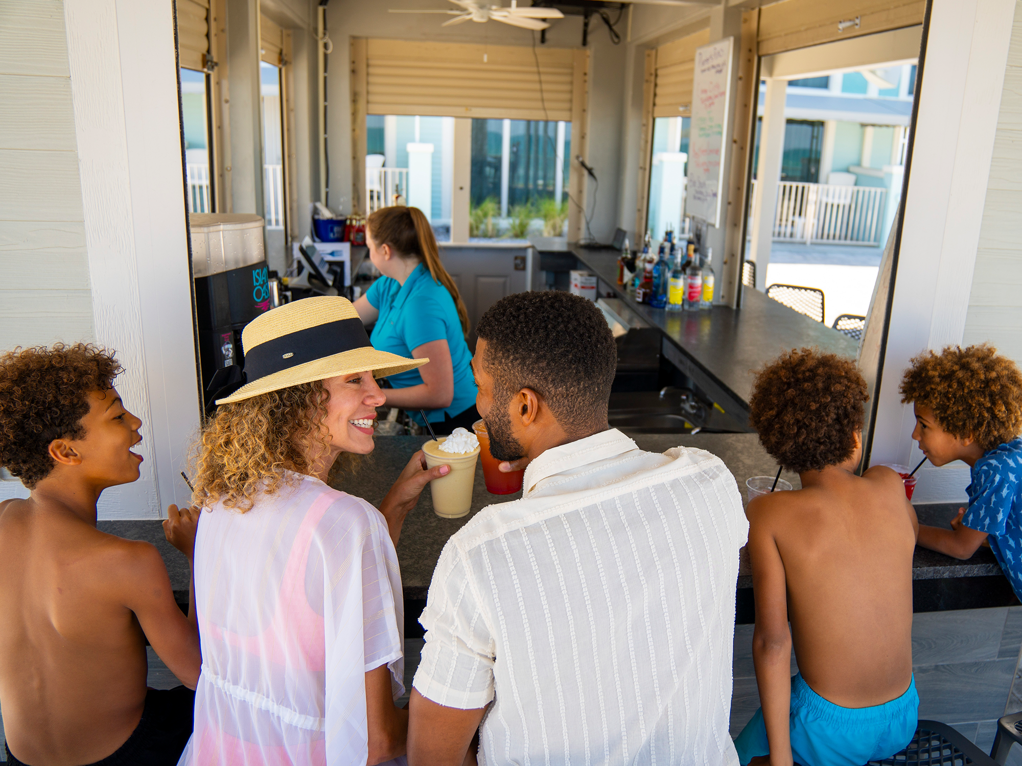 Family sitting around a table in a modern kitchen with large windows.