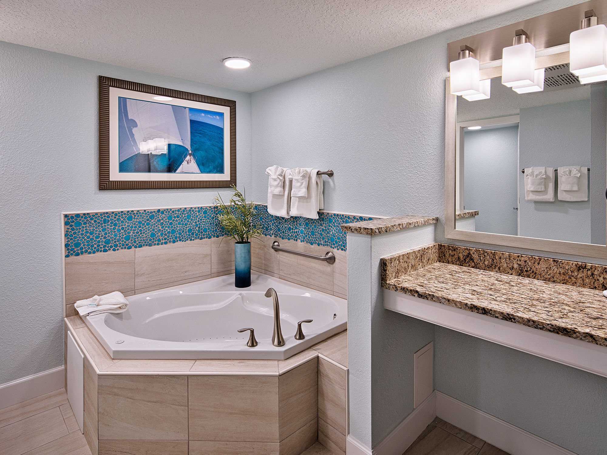Bathroom with corner bathtub, mirror, and decorative elements.