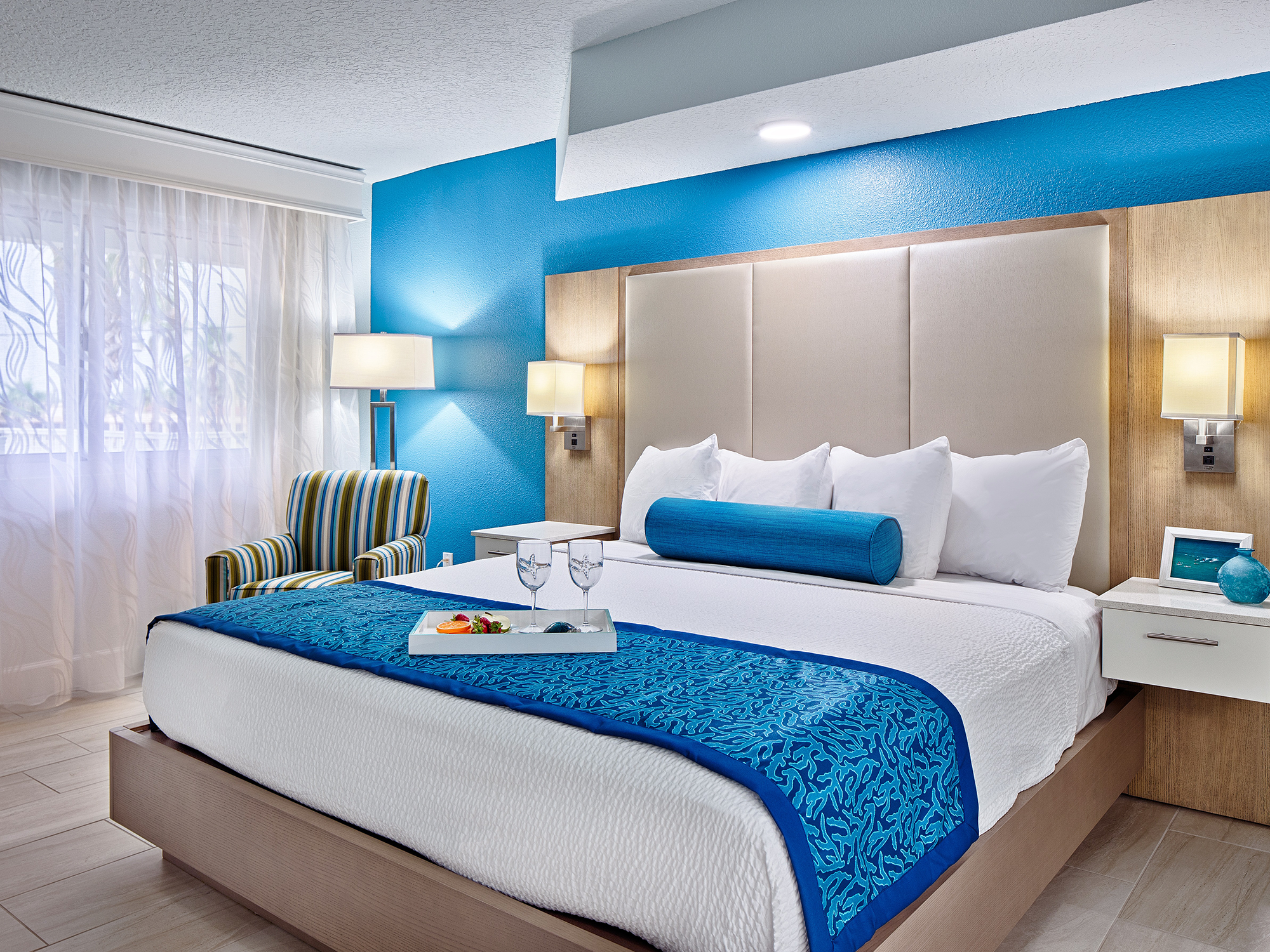 Modern bedroom with a bed, blue accent, and decorative pillows.