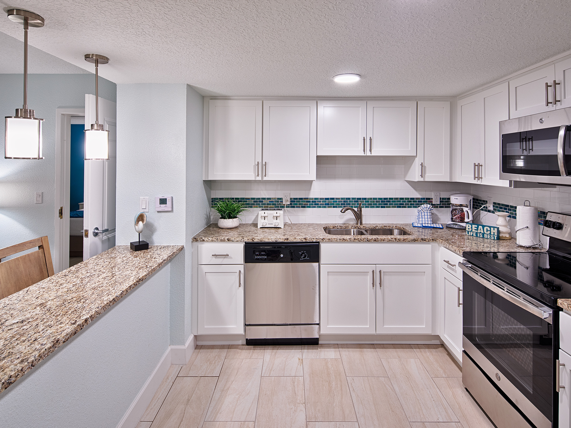 Modern kitchen with white cabinets, stainless steel appliances, and granite countertops.