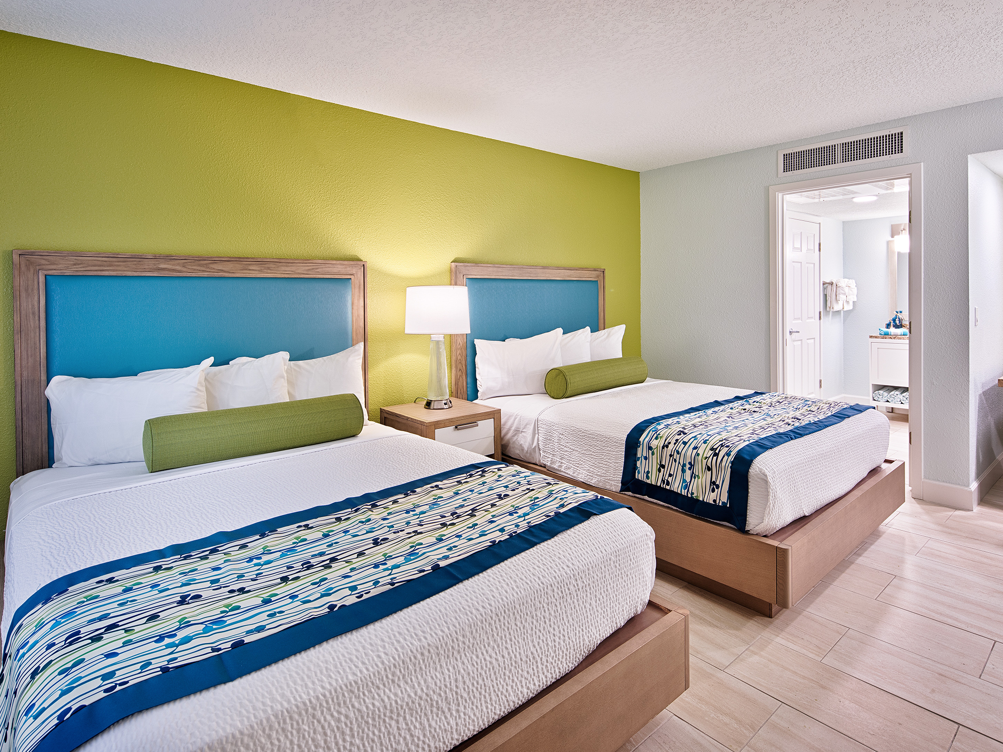 Two beds in a room with green walls and a lamp.