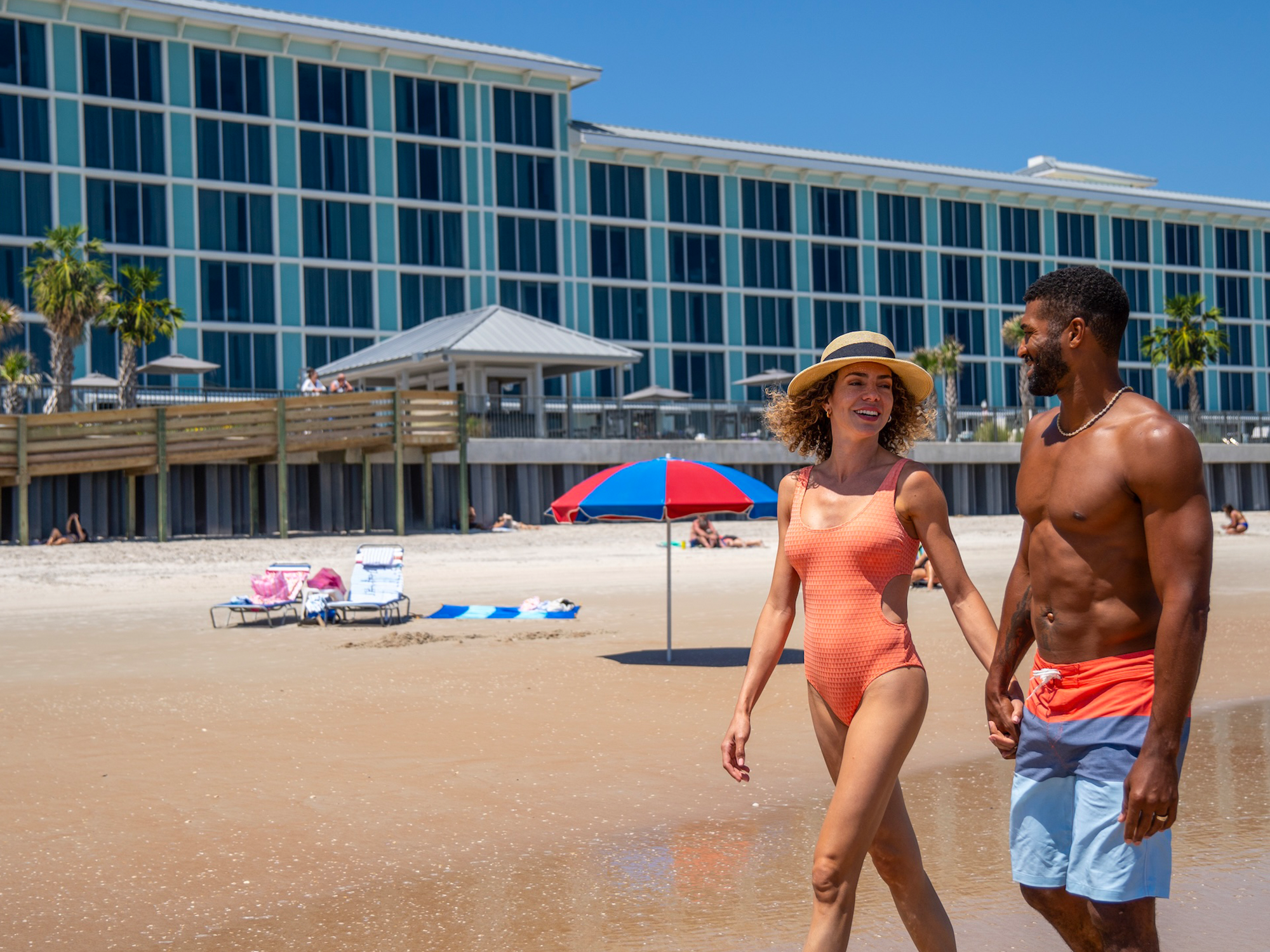 Two people walking on a beach with the grand seas resort in the background