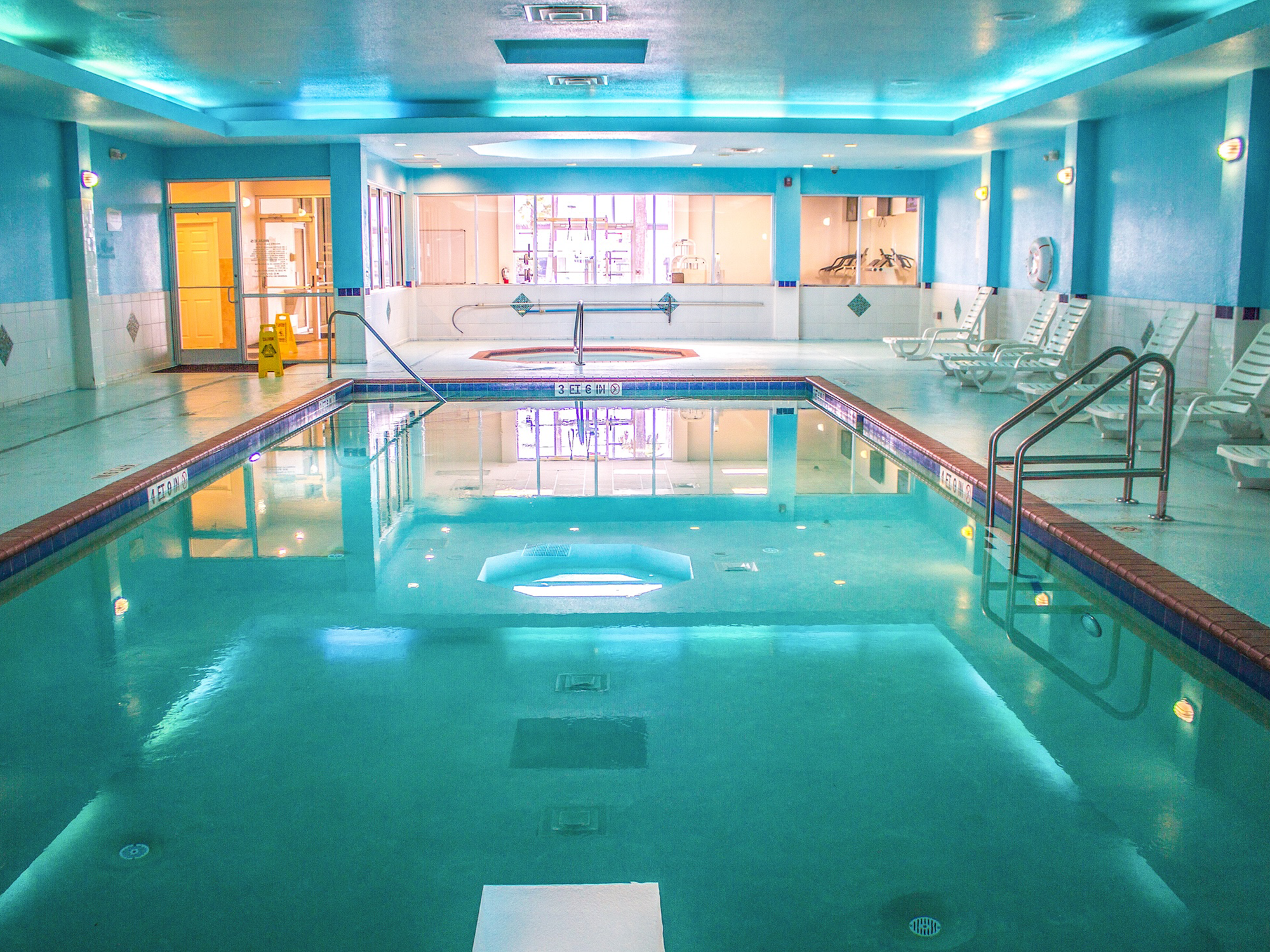 Indoor pool with blue water and tiled walls, surrounded by lounge chairs.