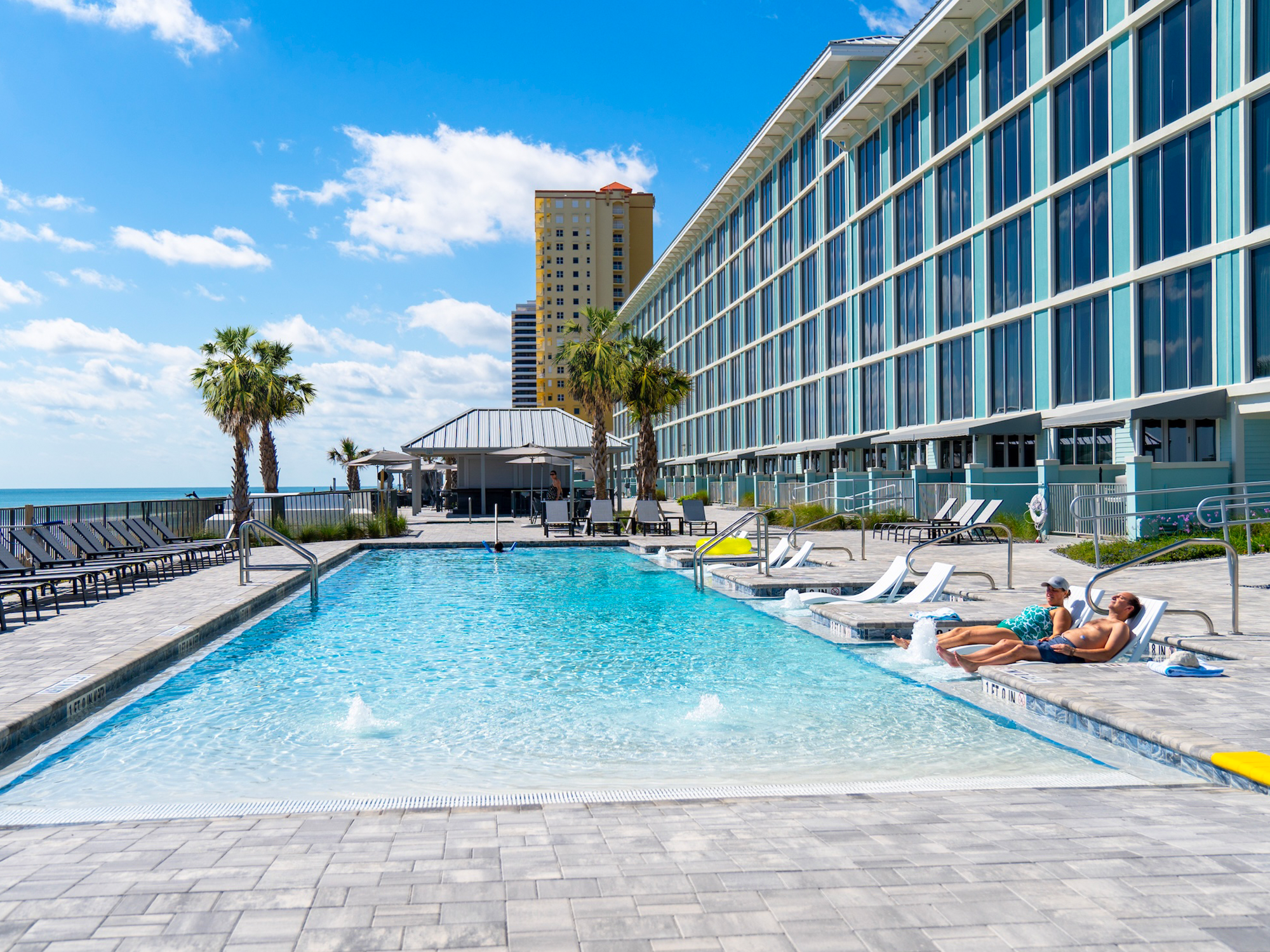 Pool area with lounge chairs and people near grand seas resort by the beach