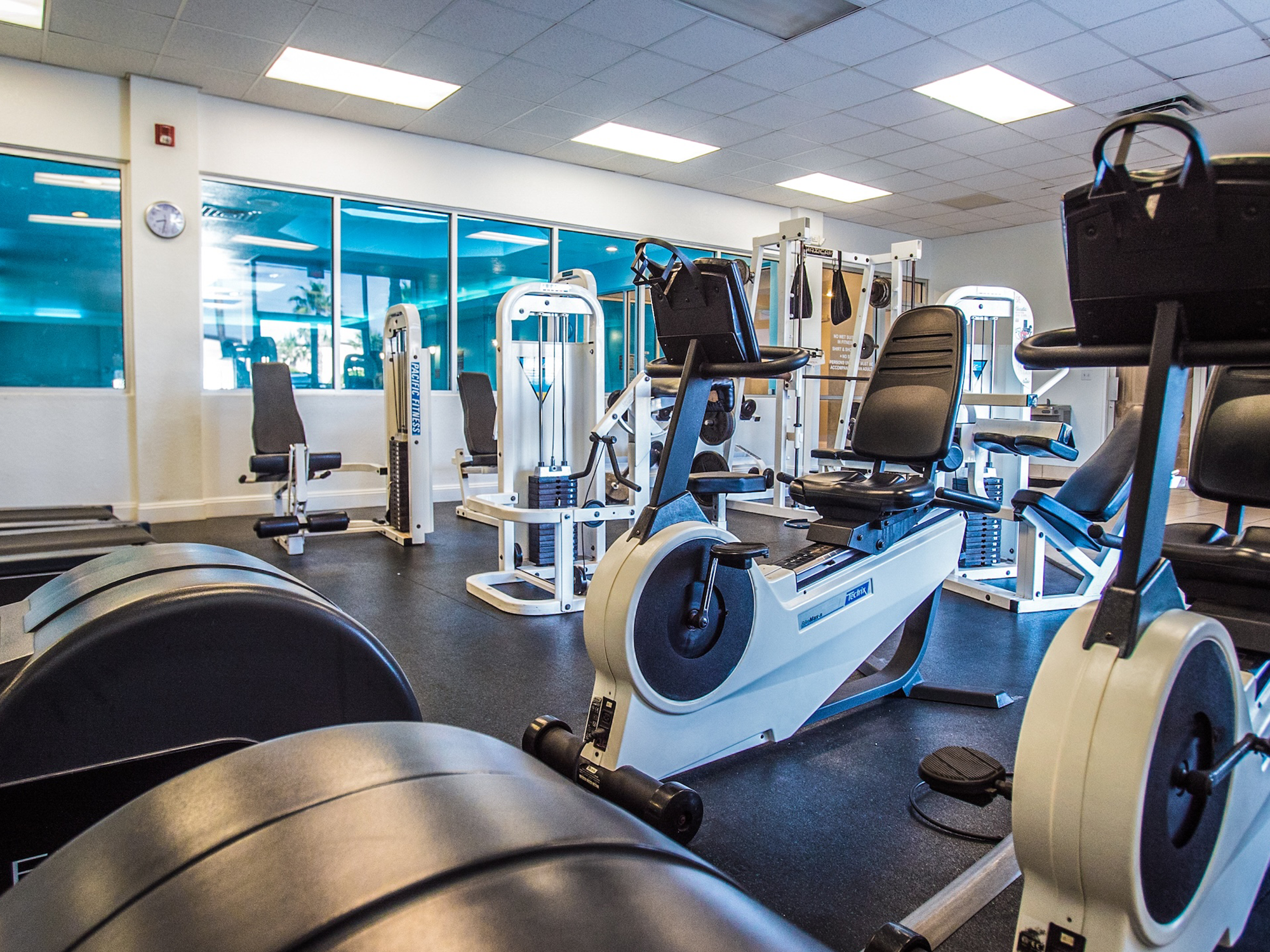 Gym interior with exercise equipment including treadmills and stationary bikes.
