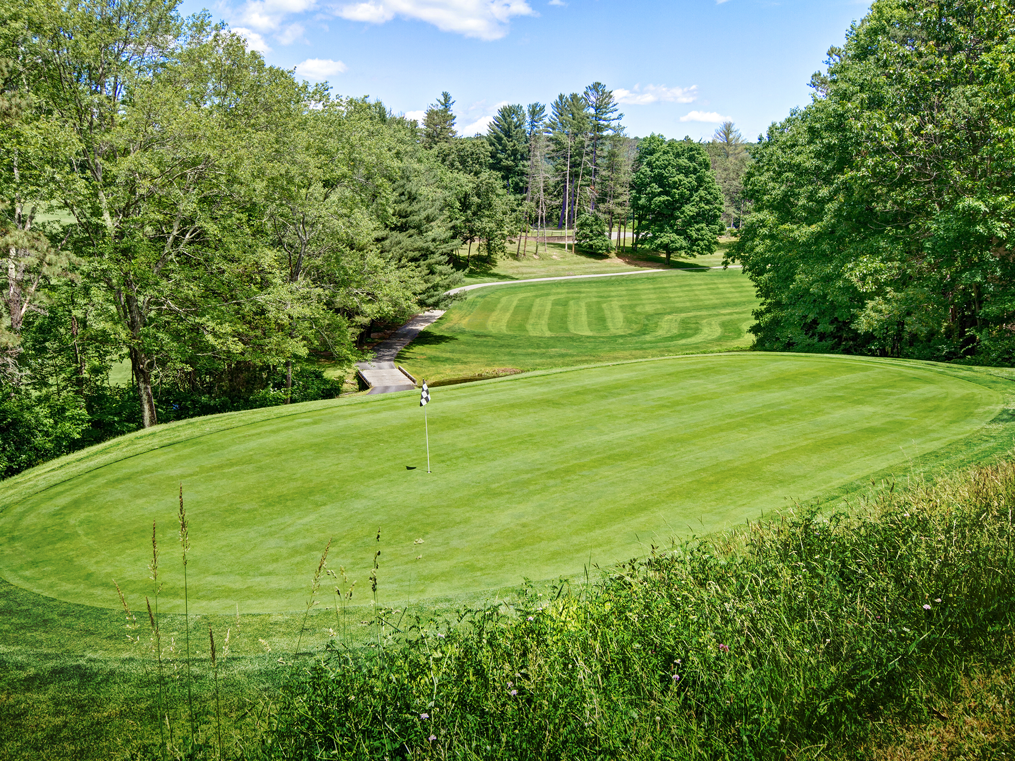Golf course with green grass and trees under a clear blue sky