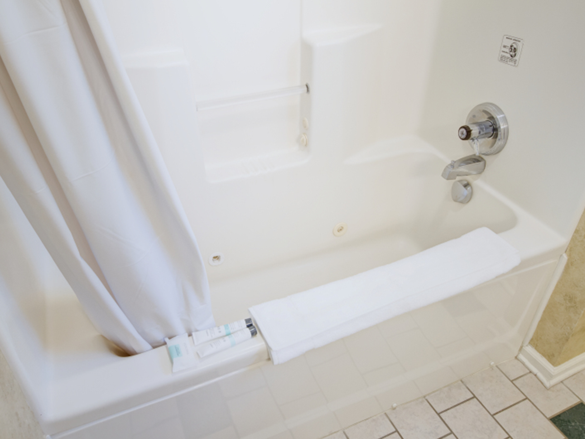 Bathroom with a bathtub, shower curtain, and tiled floor.