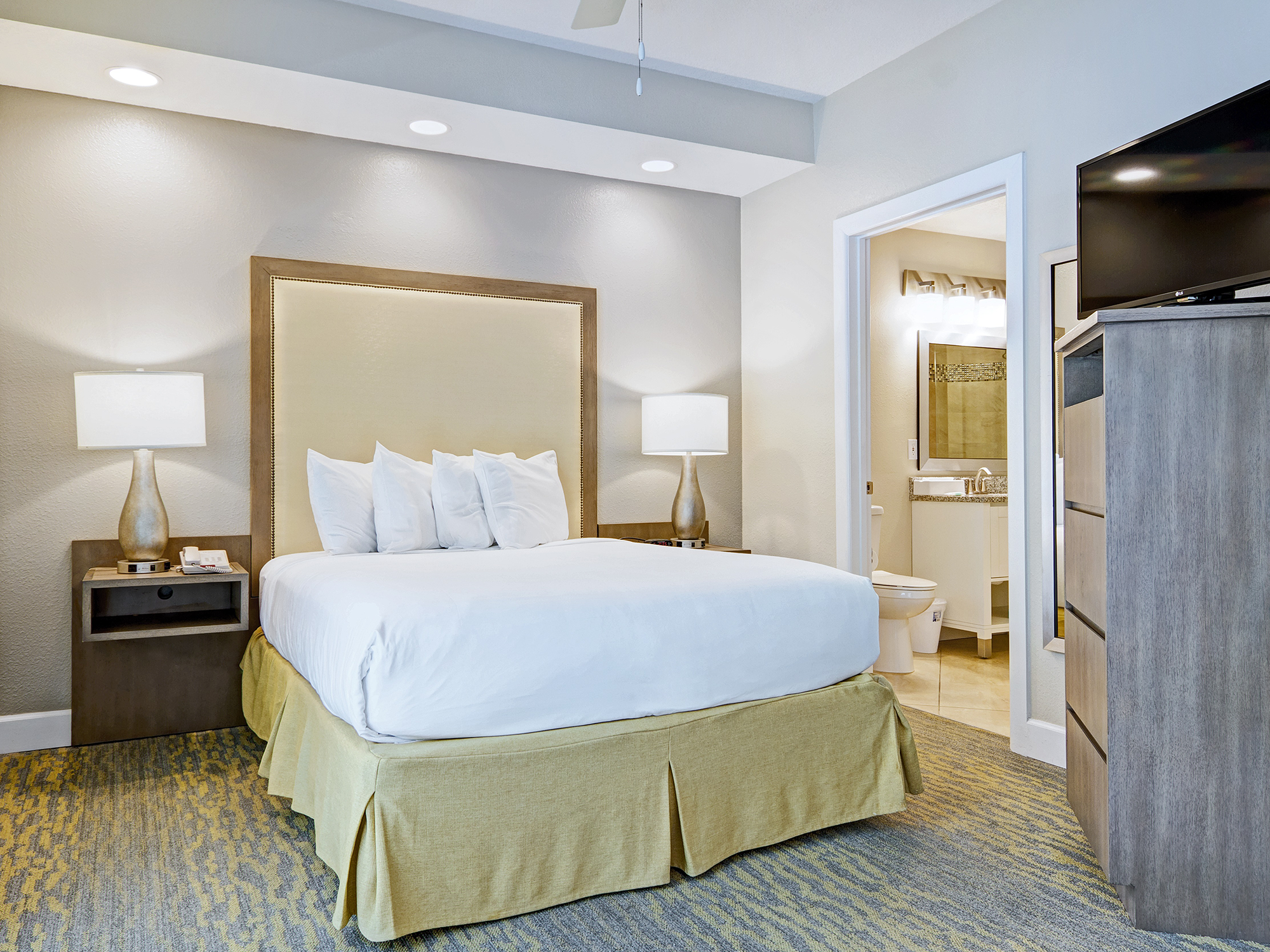 Modern summer bay orlando resort hotel room with bed, nightstands, and kitchenette.