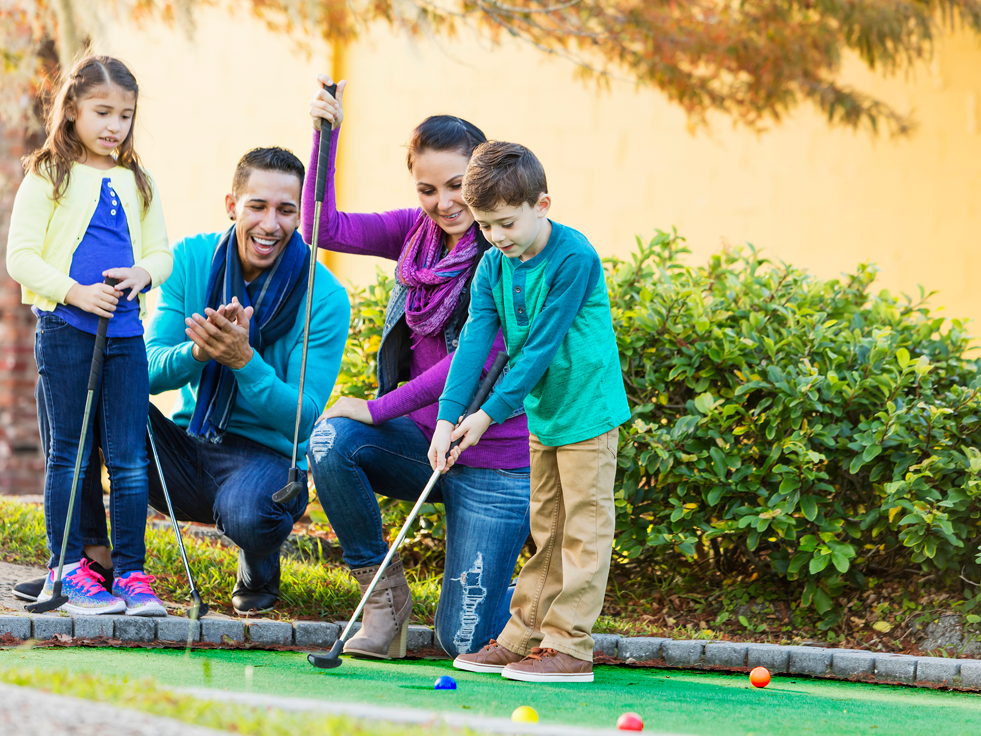 Family playing mini golf together on a sunny day